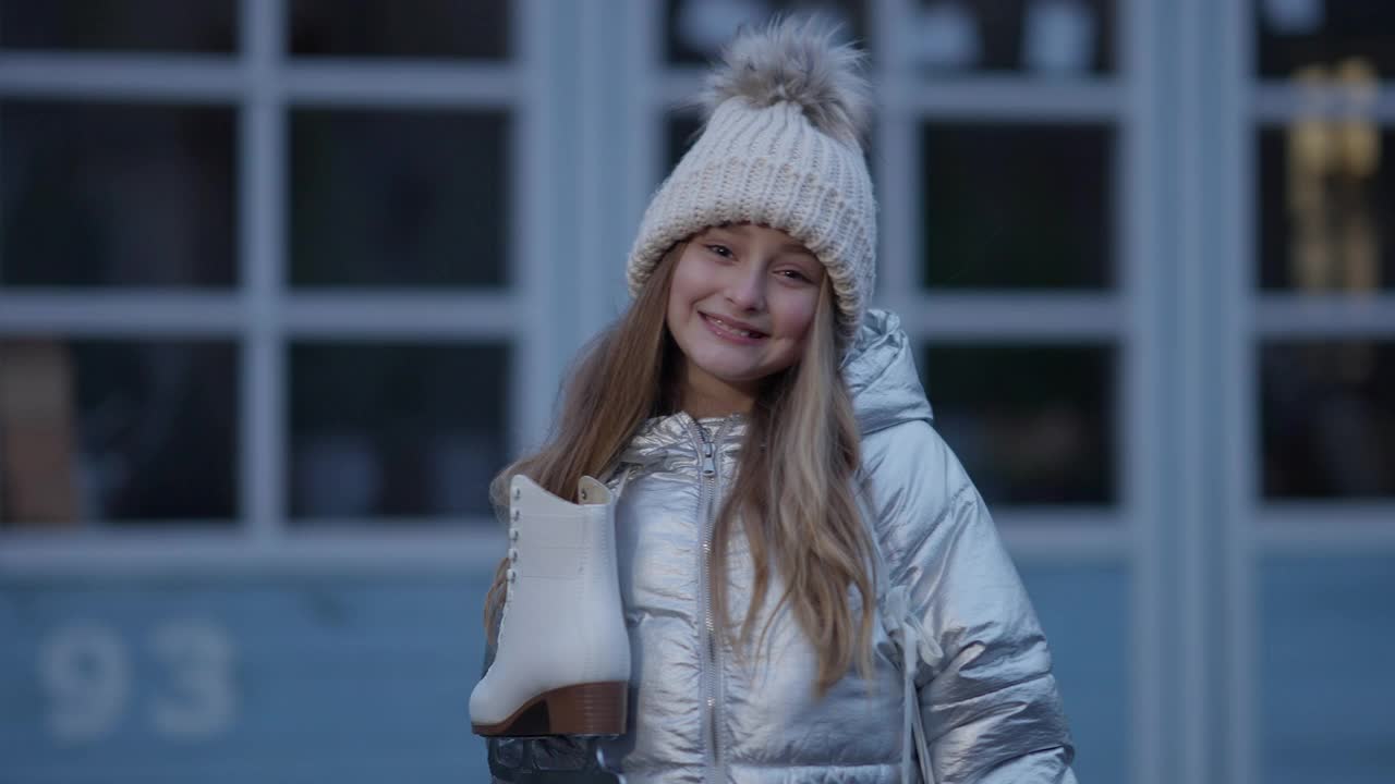 中景可爱微笑的白人女孩摆姿势在溜冰场溜冰鞋挂在脖子上。快乐的孩子在户外的溜冰场吹牛的肖像。运动与生活理念视频素材