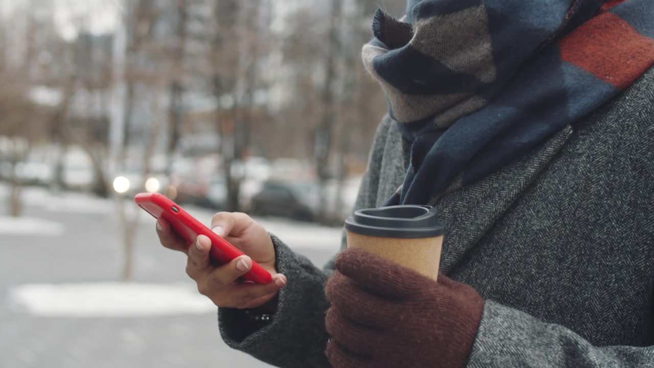 一名年轻黑人在户外拿着咖啡用手机视频素材