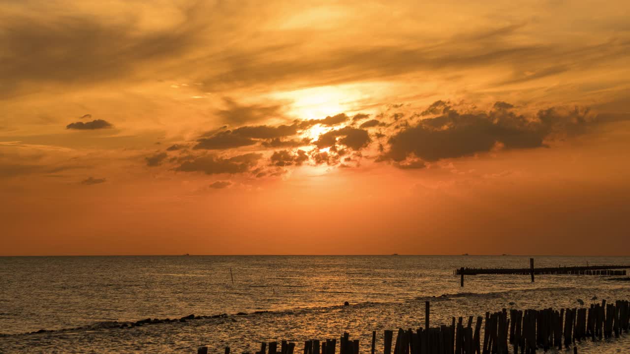 天空和晚云都是橙色的。太阳正落在云层后面。视频素材