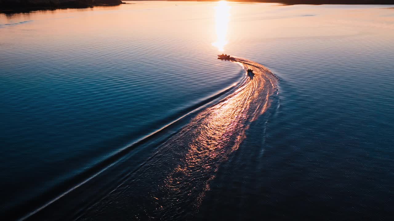 日落时船只的运动。傍晚的河上，摩托艇在水面上留下了惊人的风景。鸟瞰图。视频素材