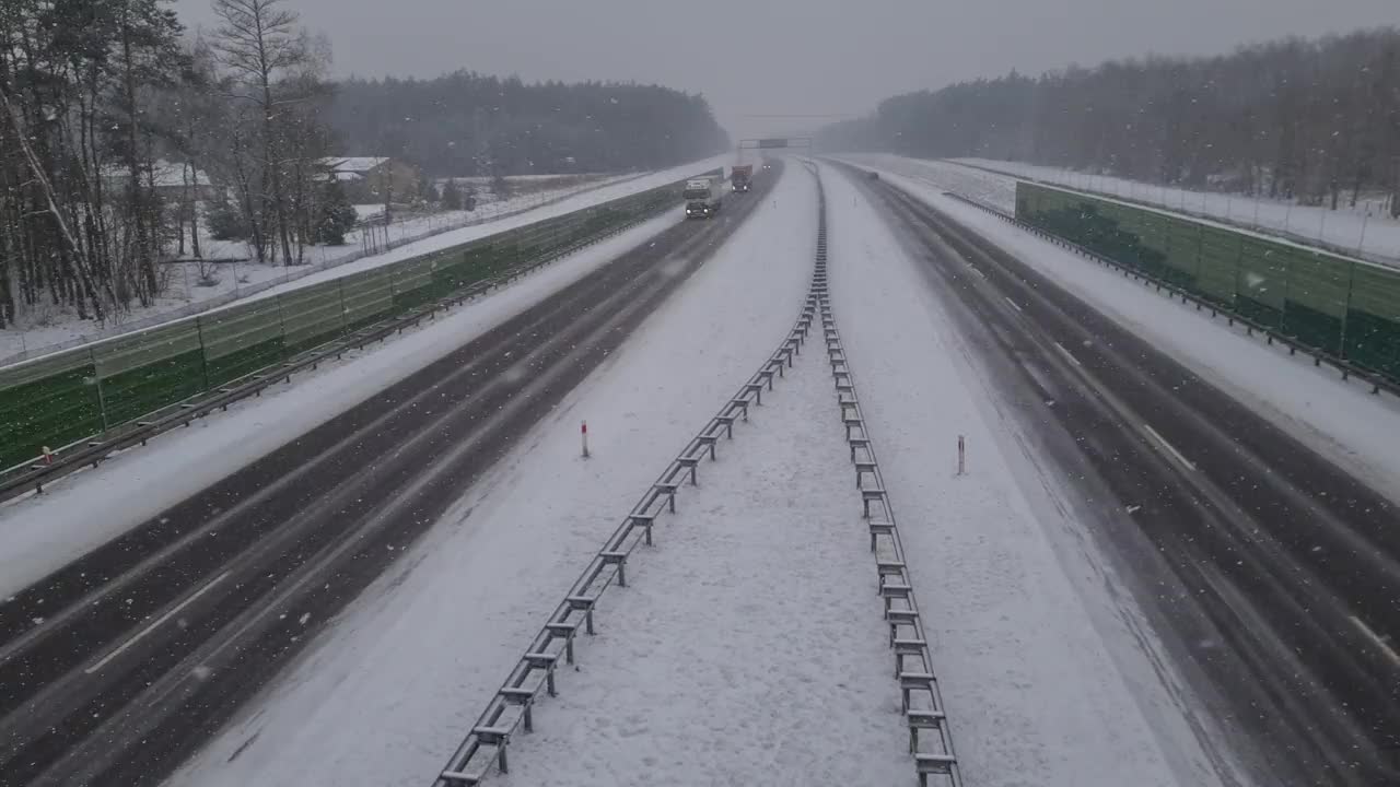 从桥上俯瞰，在暴风雪中高速公路上行驶的汽车视频下载