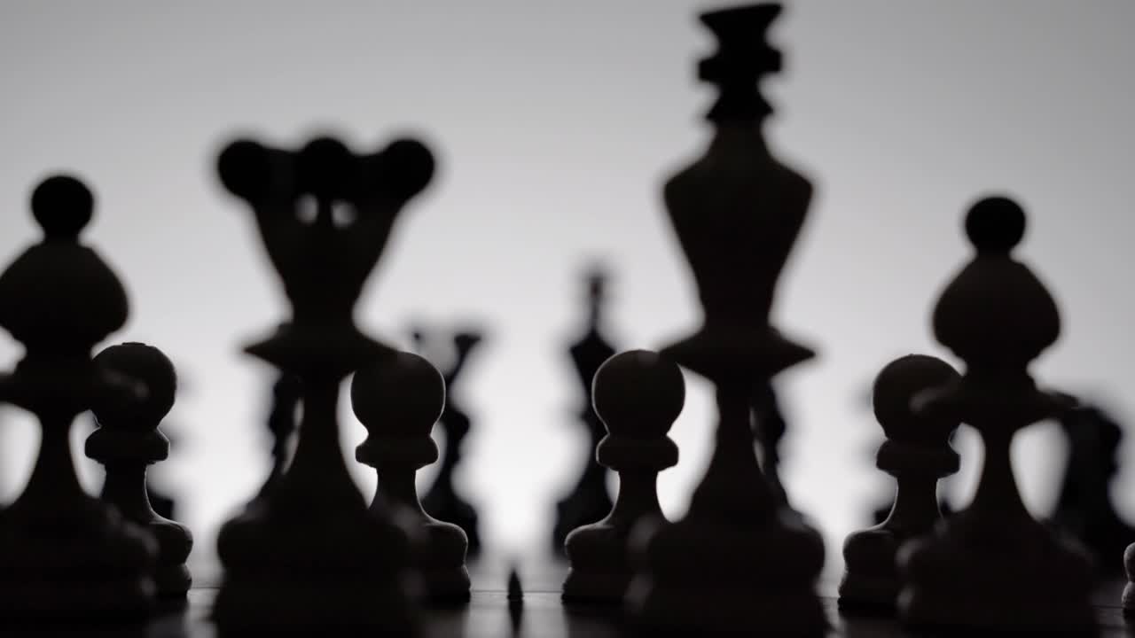 国际象棋的游戏。棋盘上的棋子在白色的剪影。商业观念、竞争观念和战略观念。黑白慢镜头。受欢迎的国王的棋子打开和斯堪的纳维亚防御视频素材