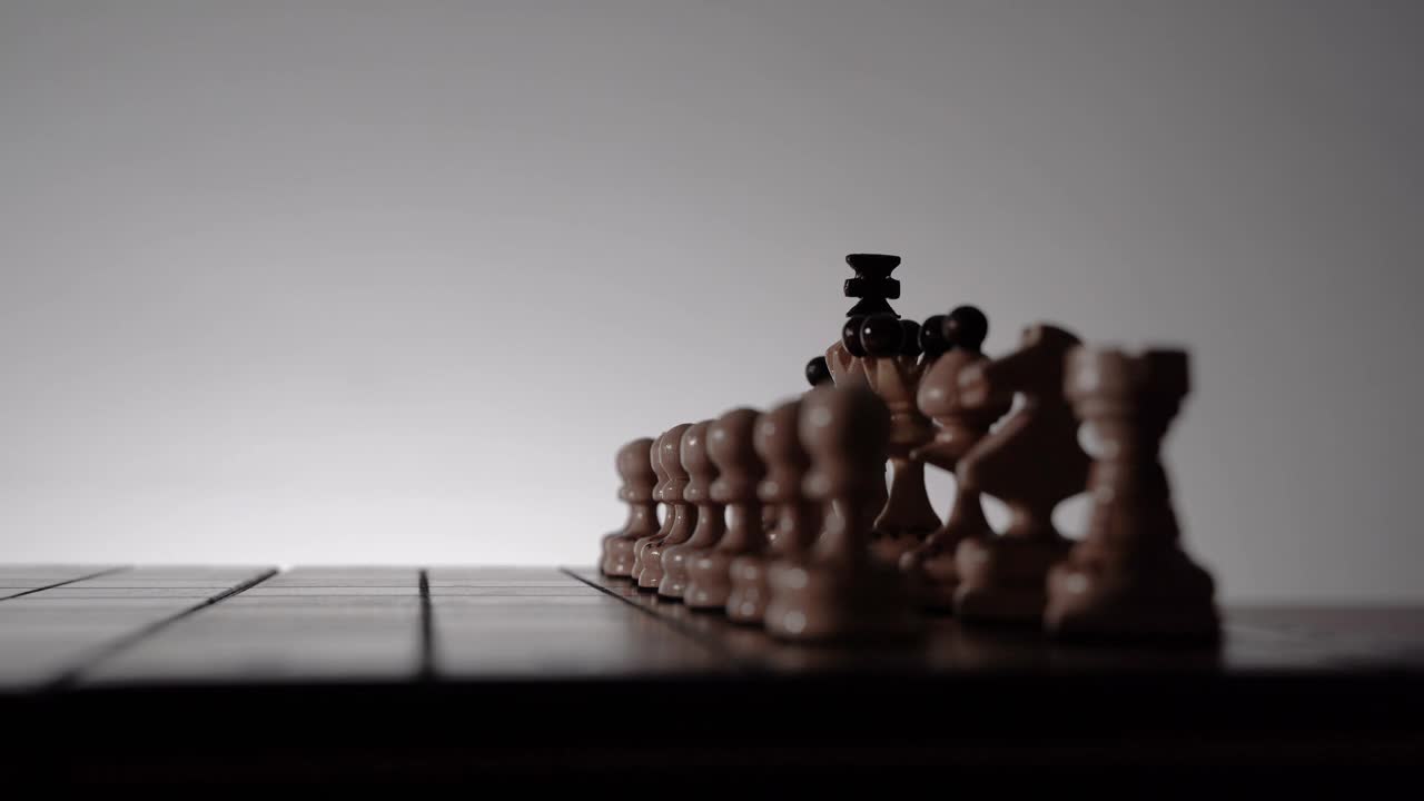 国际象棋的游戏。棋盘与棋子的剪影在白色的背景。商业理念、竞争和战略理念的概念。黑白经典艺术照片。传统的国王的卒开视频素材