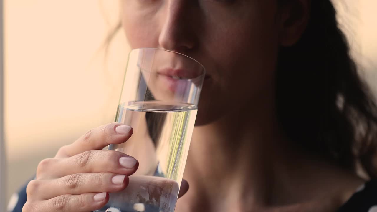 近距离观看年轻女子饮用一杯静止的天然水视频素材