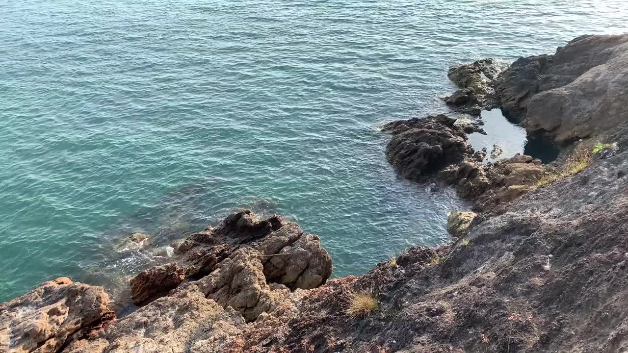 阳光灿烂的日子，海浪拍打着岩石视频素材