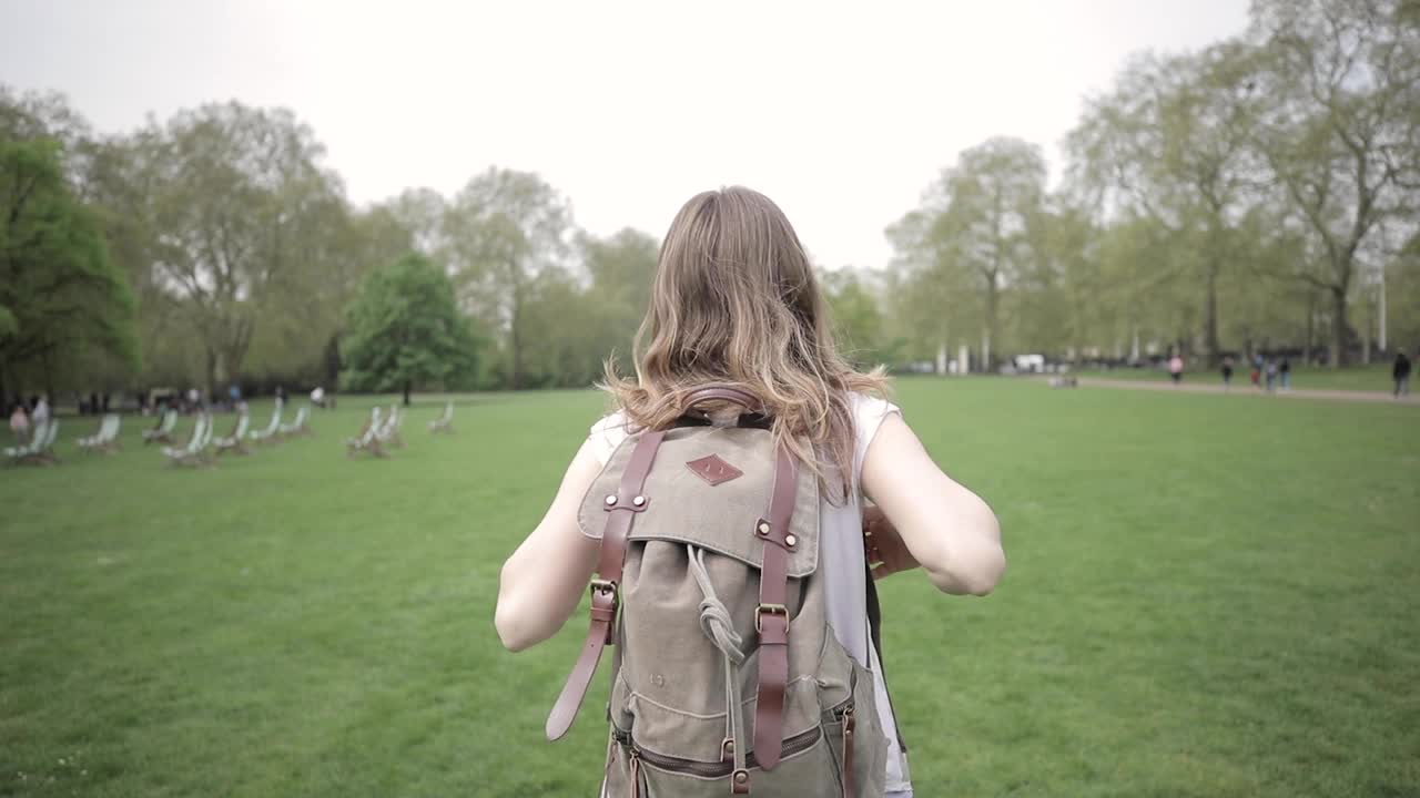 在英国伦敦的一个公园里散步的女人的后视图视频素材