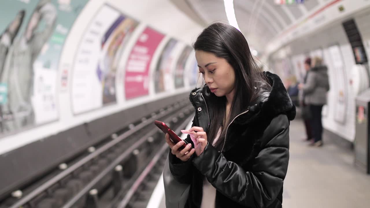 一名中国女子在地铁站用智能手机等待视频素材