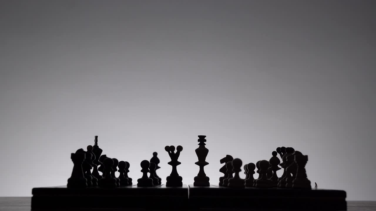 国际象棋的游戏。棋盘与棋子的剪影在白色的背景。商业理念、竞争和战略理念的概念。黑白经典艺术照片。视频素材