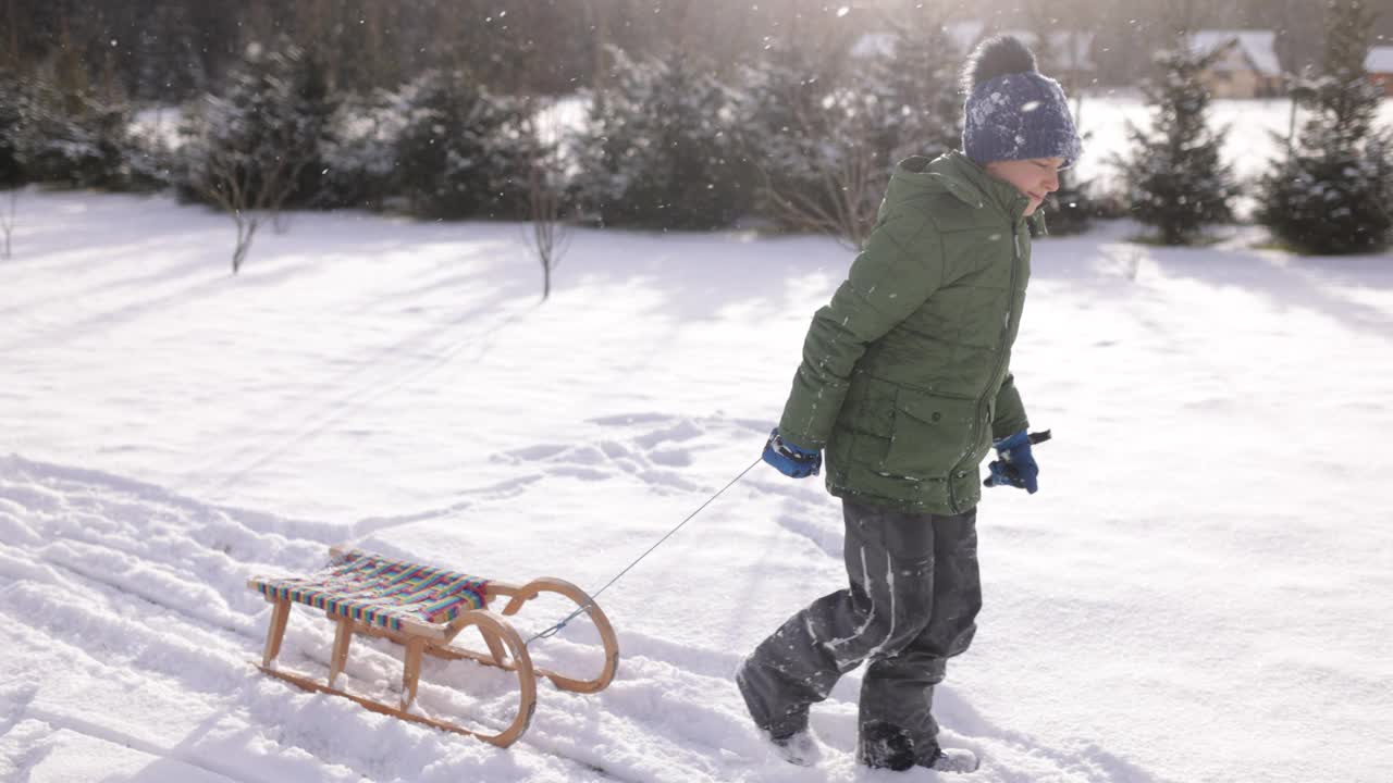 一个小男孩在冬天拉雪橇视频素材