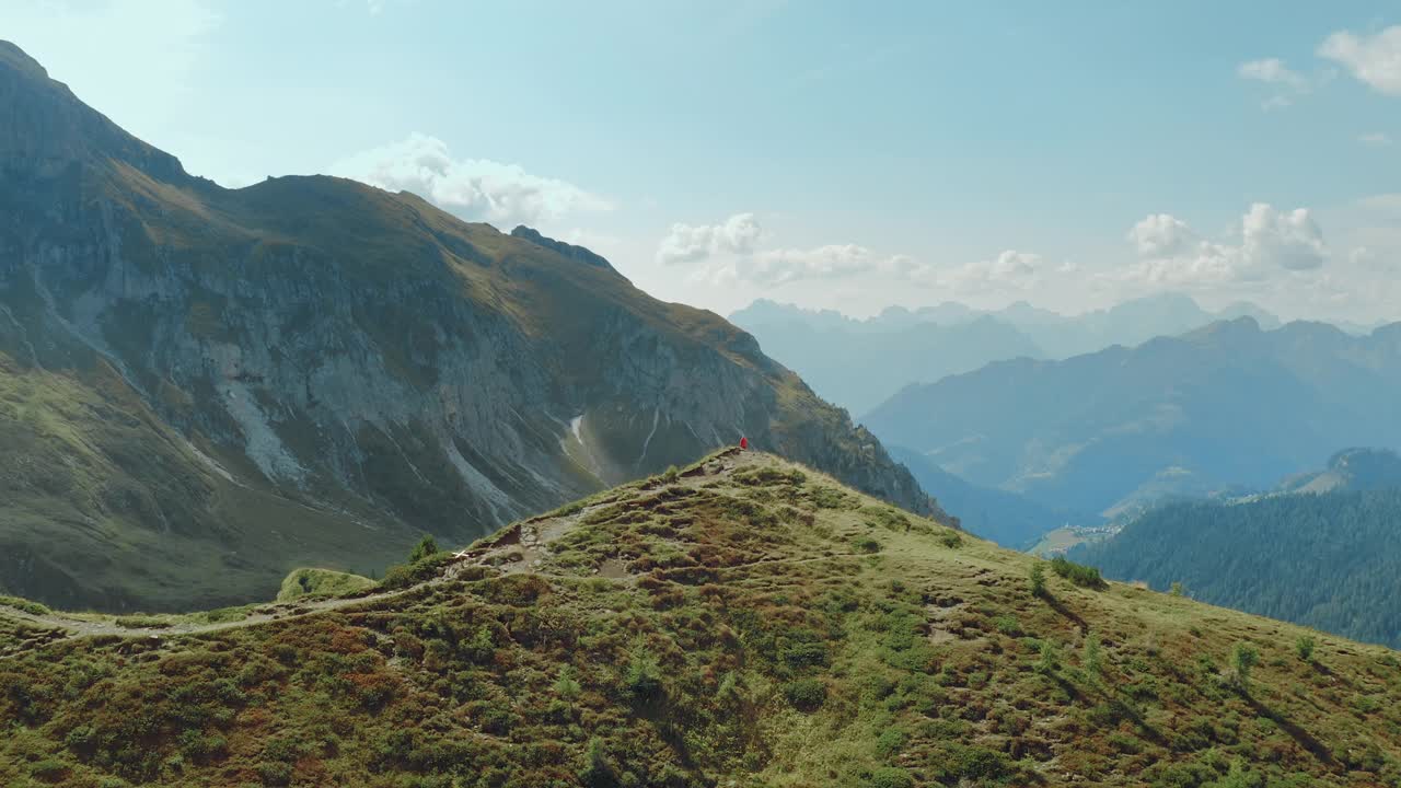 一个年轻的健康的旅游女孩在一个阳光明媚的日子站在风景如画的多洛米特悬崖上的鸟瞰图。视频素材