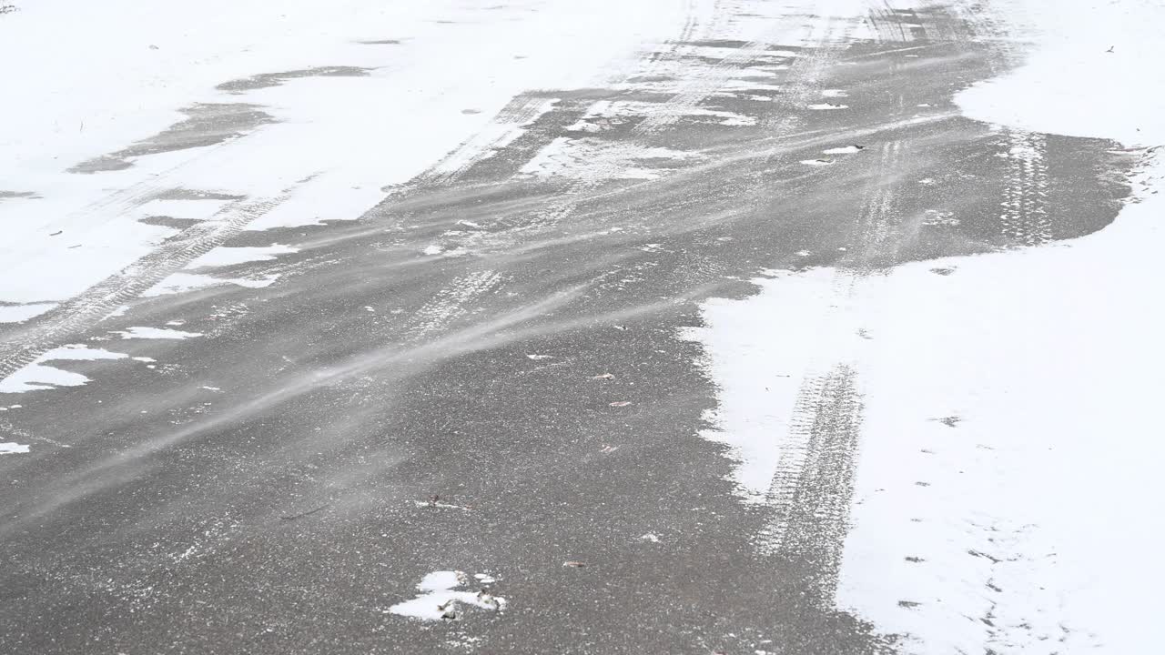 凛冽的寒风吹过柏油路面上的粉末雪。你可以看到一辆汽车在雪地上留下的痕迹。Bandenburg。德国视频素材