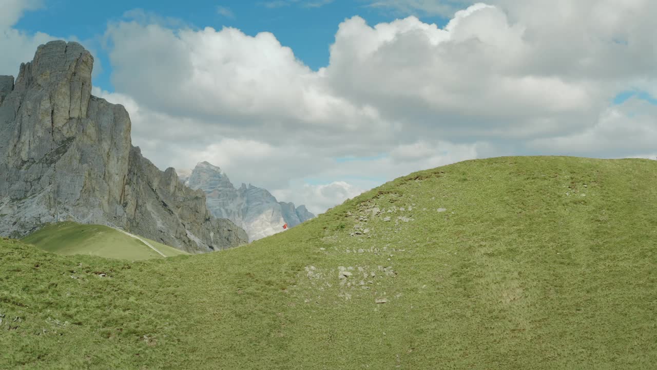 鸟瞰图的一个年轻的健康的女游客在一个风景如画的Dolomites徒步旅行在一个阳光明媚的日子俯瞰Passo Giau的空的小径。视频素材