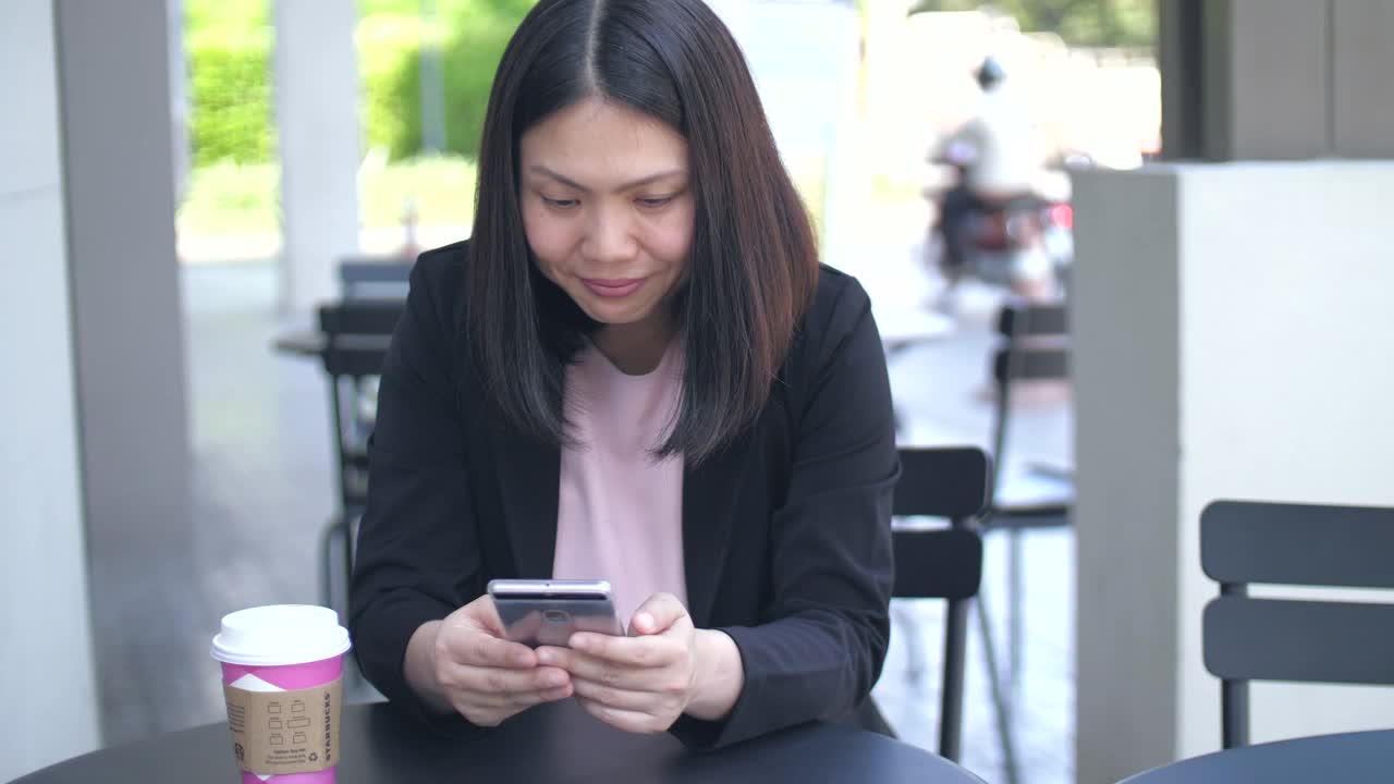 商业女性使用智能手机，在户外咖啡馆喝杯咖啡视频素材