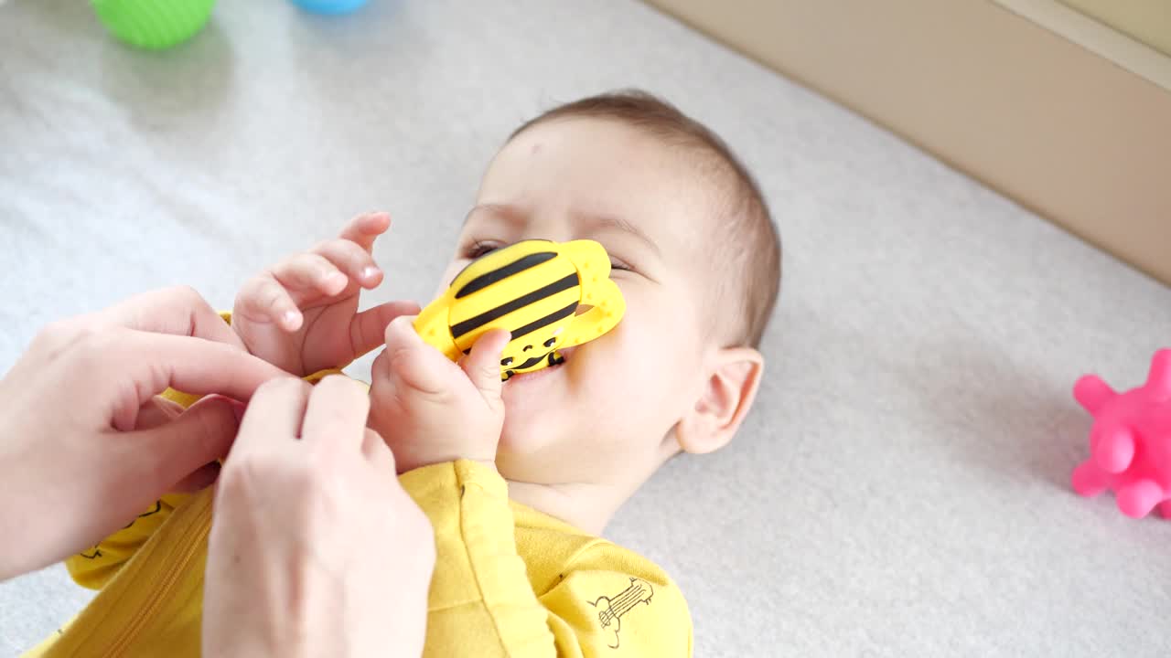 妈妈在床上给小男孩穿衣服。医学、保健、家庭、天真无邪、儿科学、幸福幼儿观念视频素材