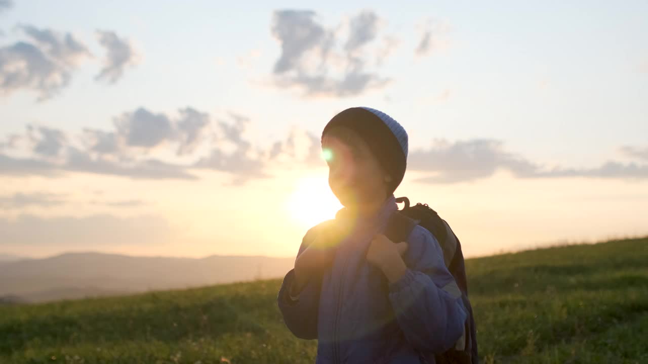 小男孩旅行者背着背包跑在日落山视频素材