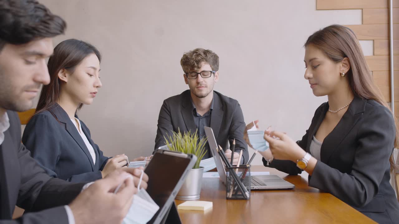 不同的商务人士戴着防护口罩一起在会议室开会。视频素材