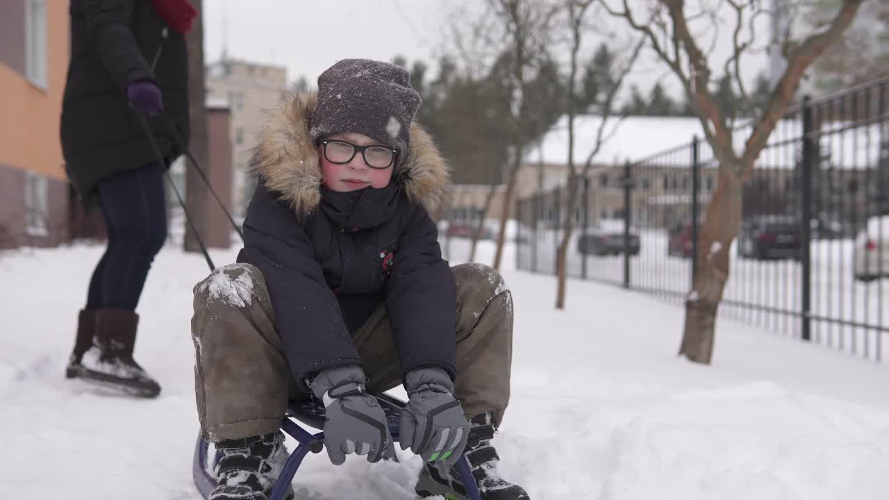 妈妈和孩子在离房子不远的院子里玩雪橇和打雪仗。视频素材