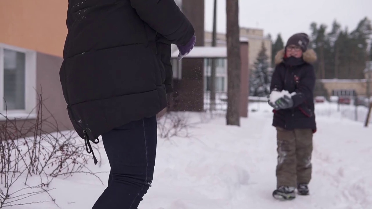 妈妈和孩子在离房子不远的院子里玩雪橇和打雪仗。视频素材