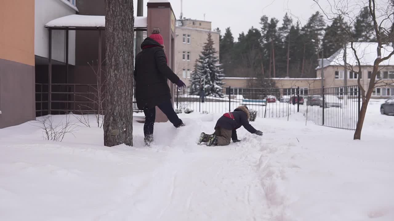 妈妈和孩子在离房子不远的院子里玩雪橇和打雪仗。视频素材