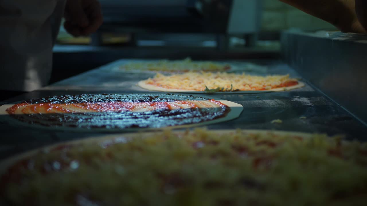 近距离观看一个男人厨师烹饪意大利披萨。在面包店的餐桌上制作披萨的过程。厨房桌上的新鲜生面团视频素材