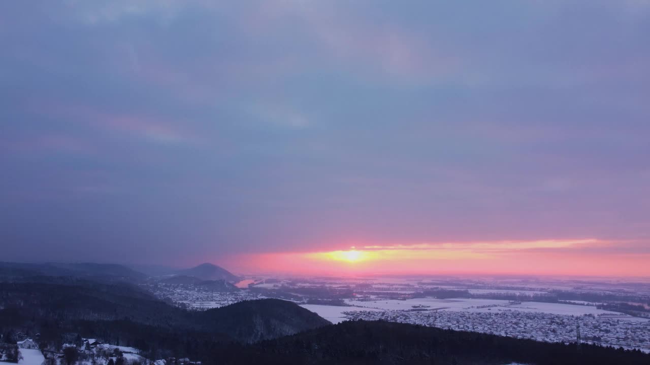 无人机在雷根斯堡附近的日出时扫过巴伐利亚的冬季景观，森林丘陵、村庄和多瑙河视频素材