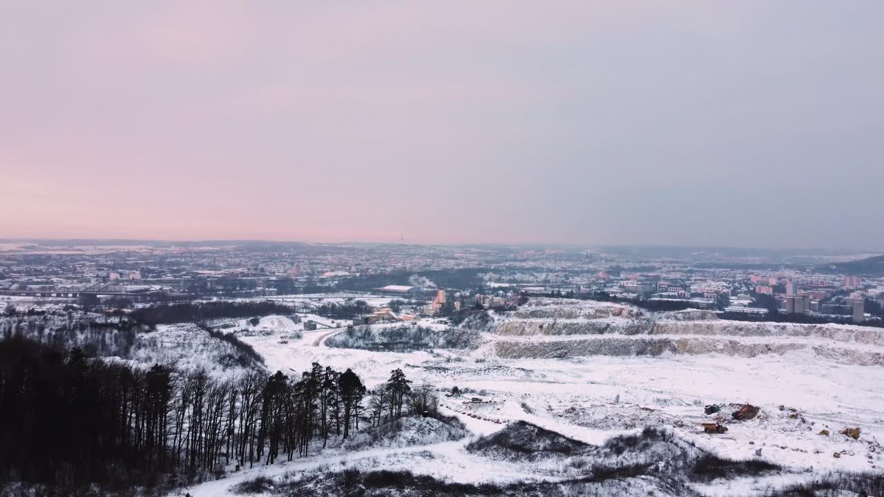 在冬天的早晨，无人机在巴伐利亚州雷根斯堡附近的大型采石场上空升起，背景是雪和城市视频素材