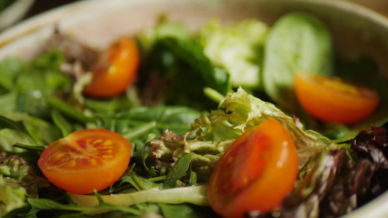 将橄榄油倒在沙拉上，配上樱桃番茄和肉酱，慢动作视频视频素材