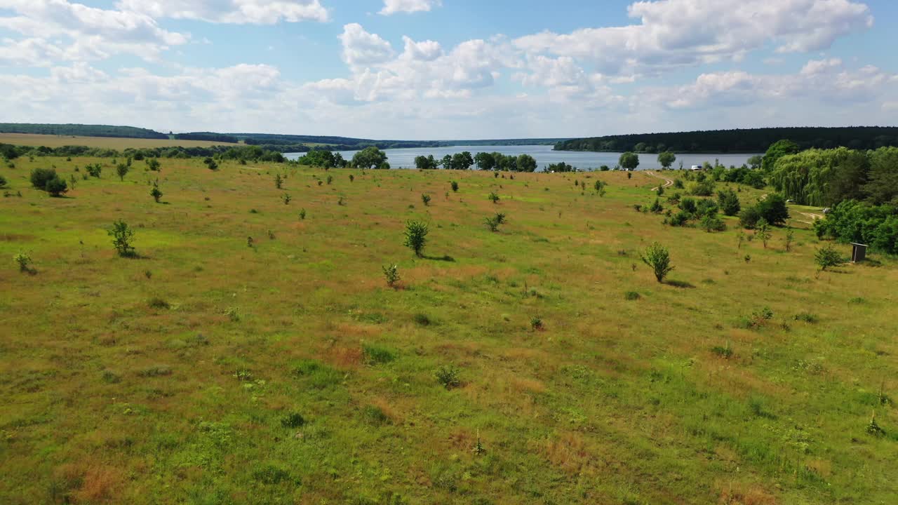 自然景观。飞过田野和河流在夏天阳光灿烂的一天。河边风景如画。蓝天下的美景。鸟瞰图。视频素材