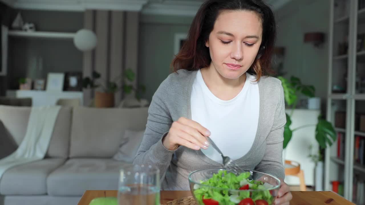 饥饿的年轻女子吃新鲜蔬菜沙拉有积极的情绪视频素材