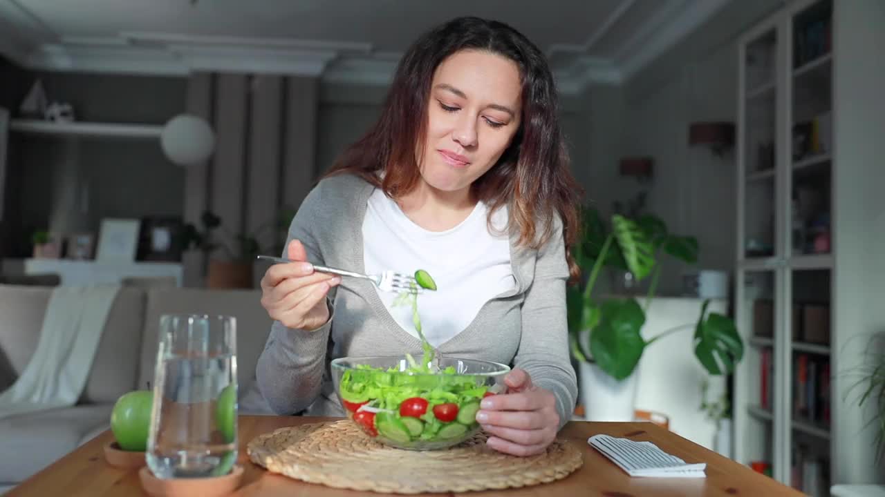 饥饿的年轻女子吃新鲜蔬菜沙拉有积极的情绪视频素材