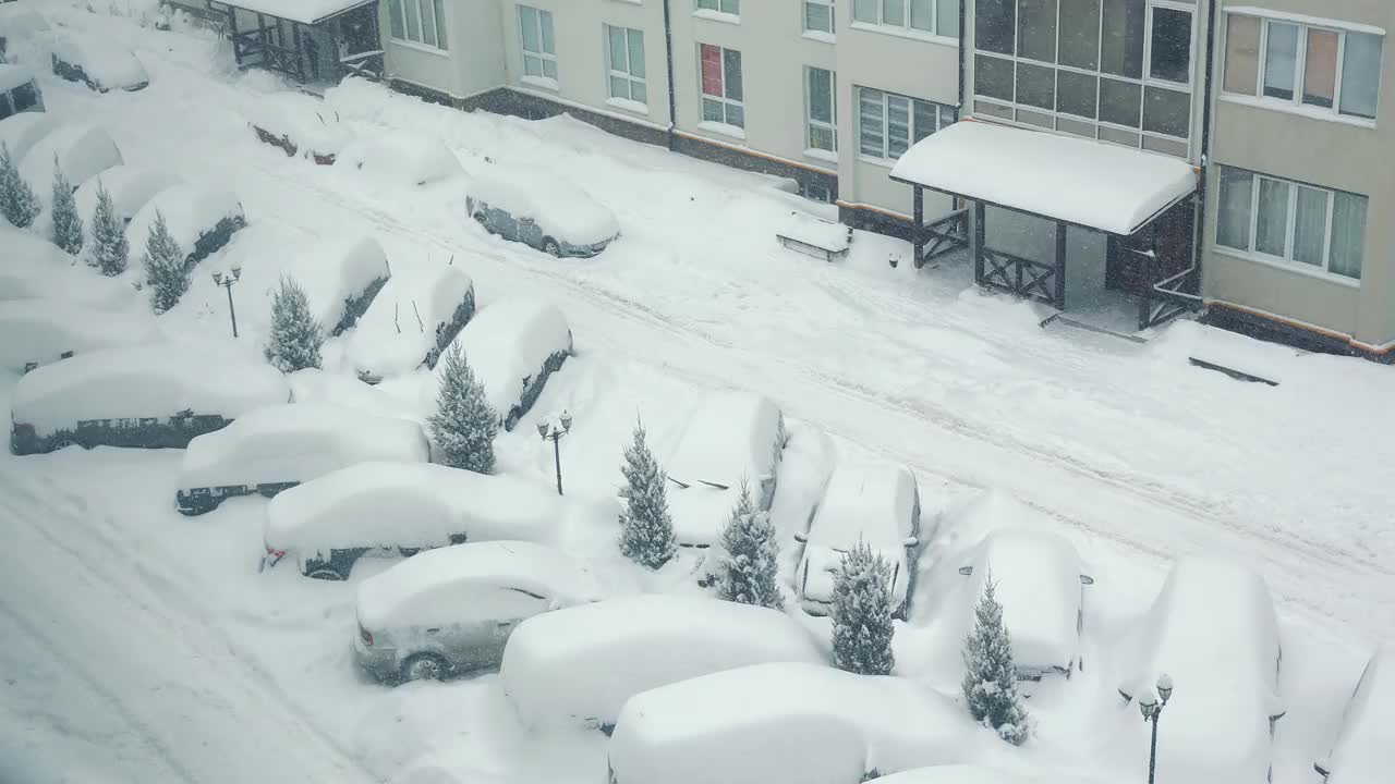 街道和汽车上都飘着雪花。院子里的停车场和汽车都被雪覆盖了视频素材