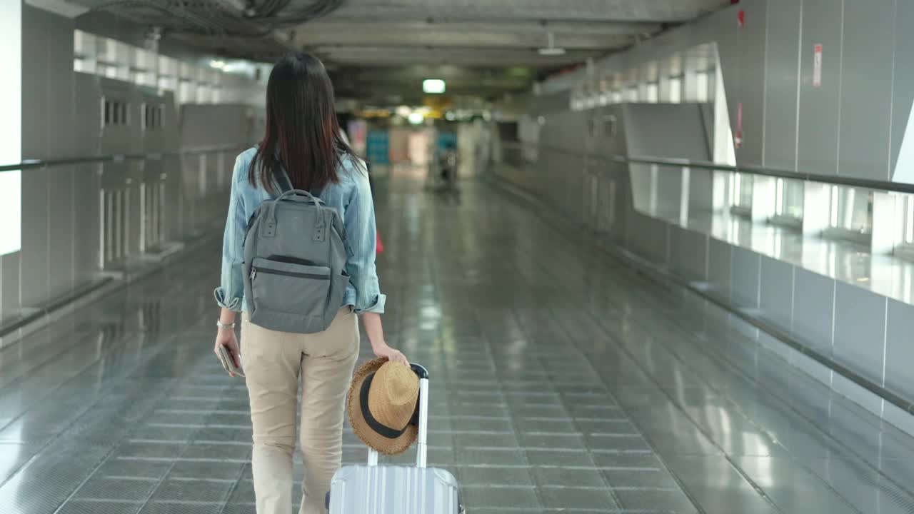 一个漫不经心的年轻女子在候机楼的门口走着。年轻妇女独自乘飞机旅行视频素材