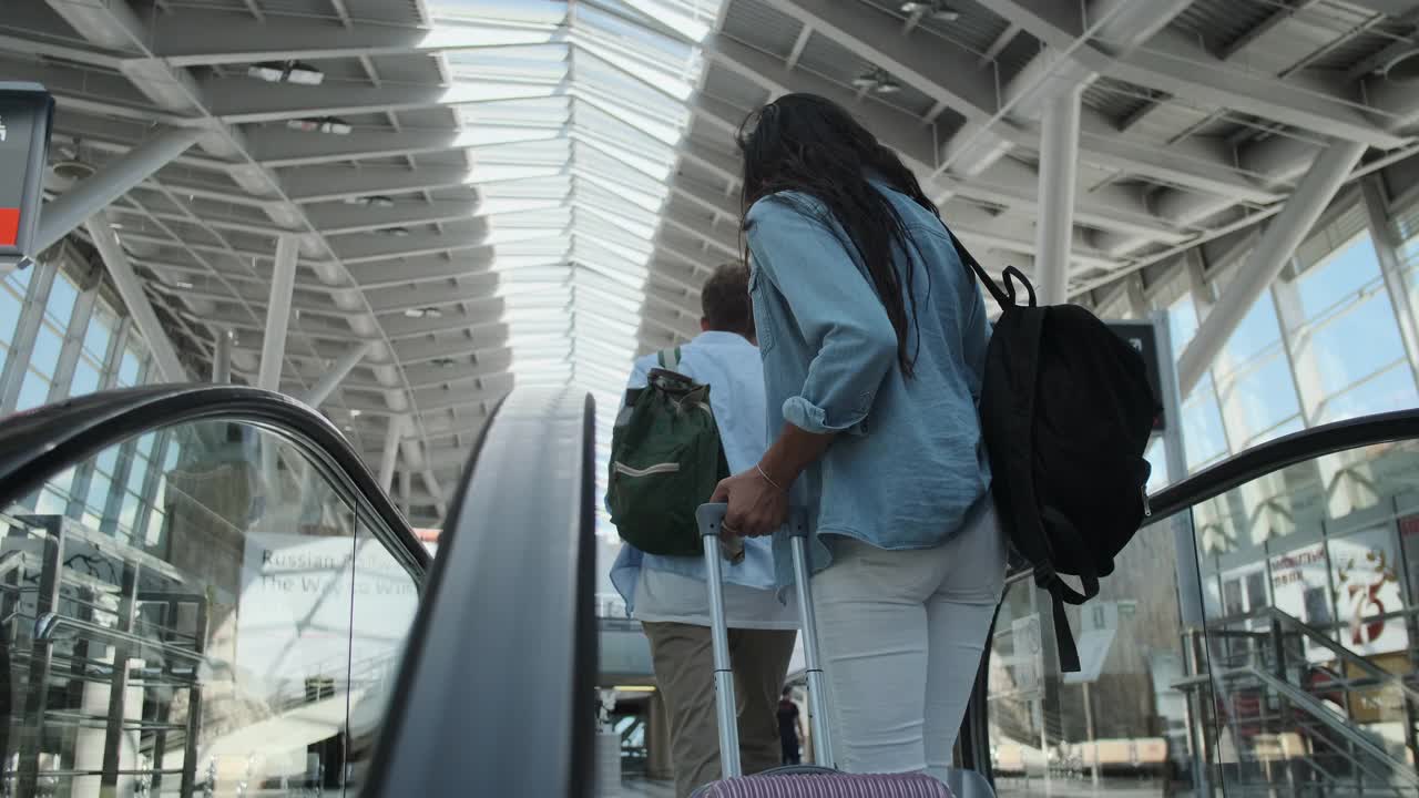 带着行李箱的旅客从自动扶梯进入车站大厅视频素材