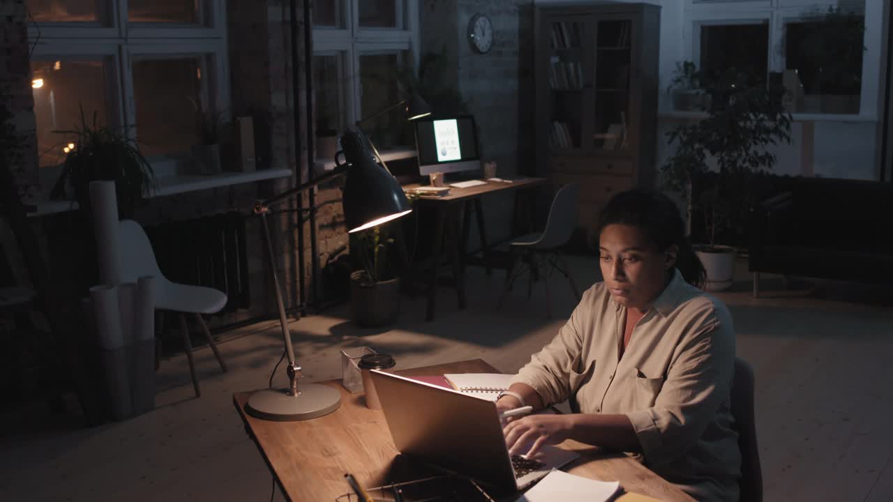 在黑暗空荡荡的办公室里独自工作的女人视频素材