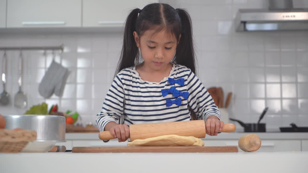 亚洲小女孩正在为面包店厨房揉面和准备面团。视频素材