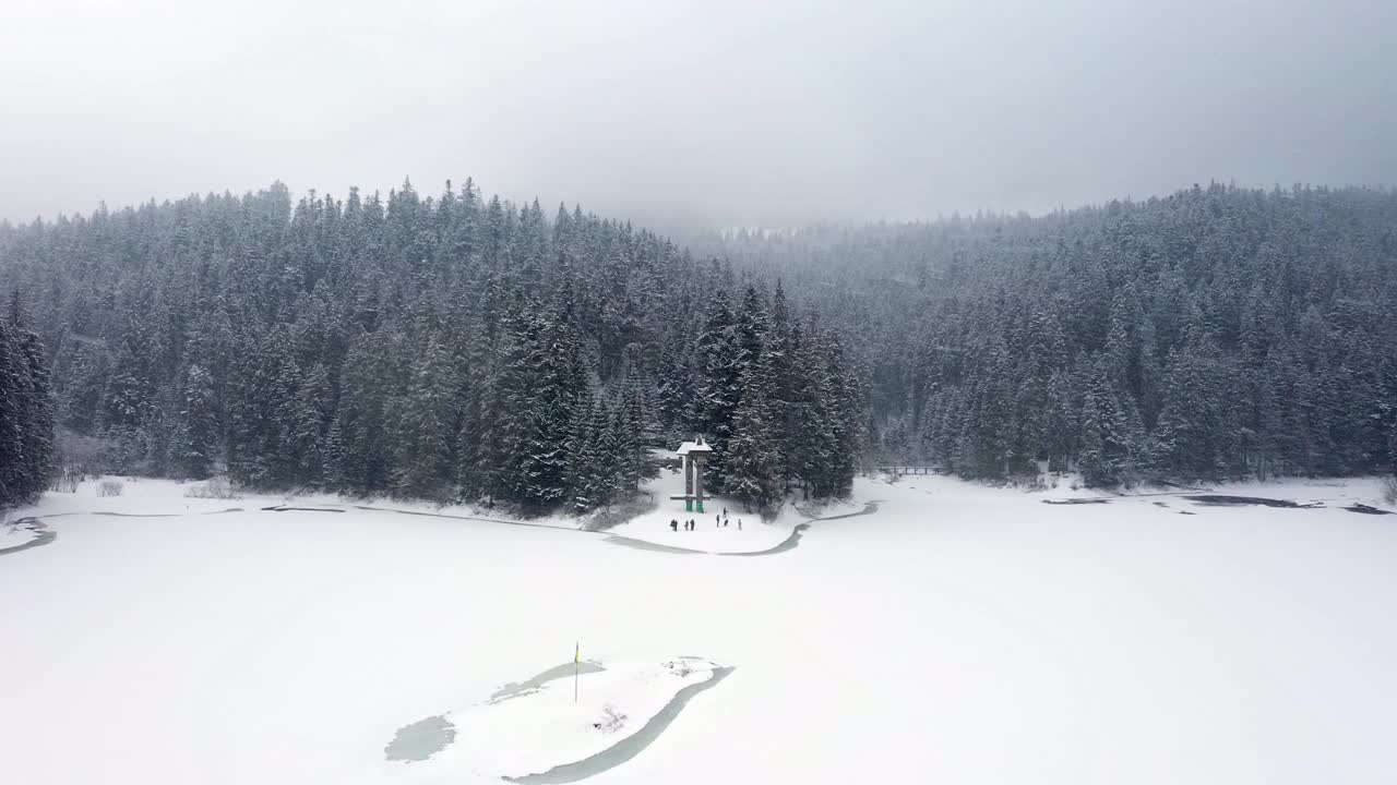 鸟瞰图冰冻森林与冰雪覆盖的湖在冬季在喀尔巴阡山脉视频素材