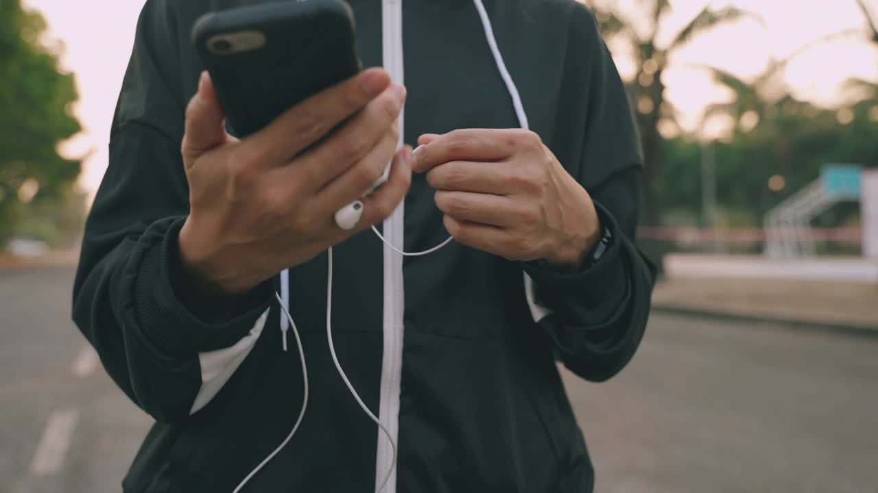 跑步的女人准备跑步，并开始在日落时分在公园里跑步，戴着耳机听着音乐。视频素材