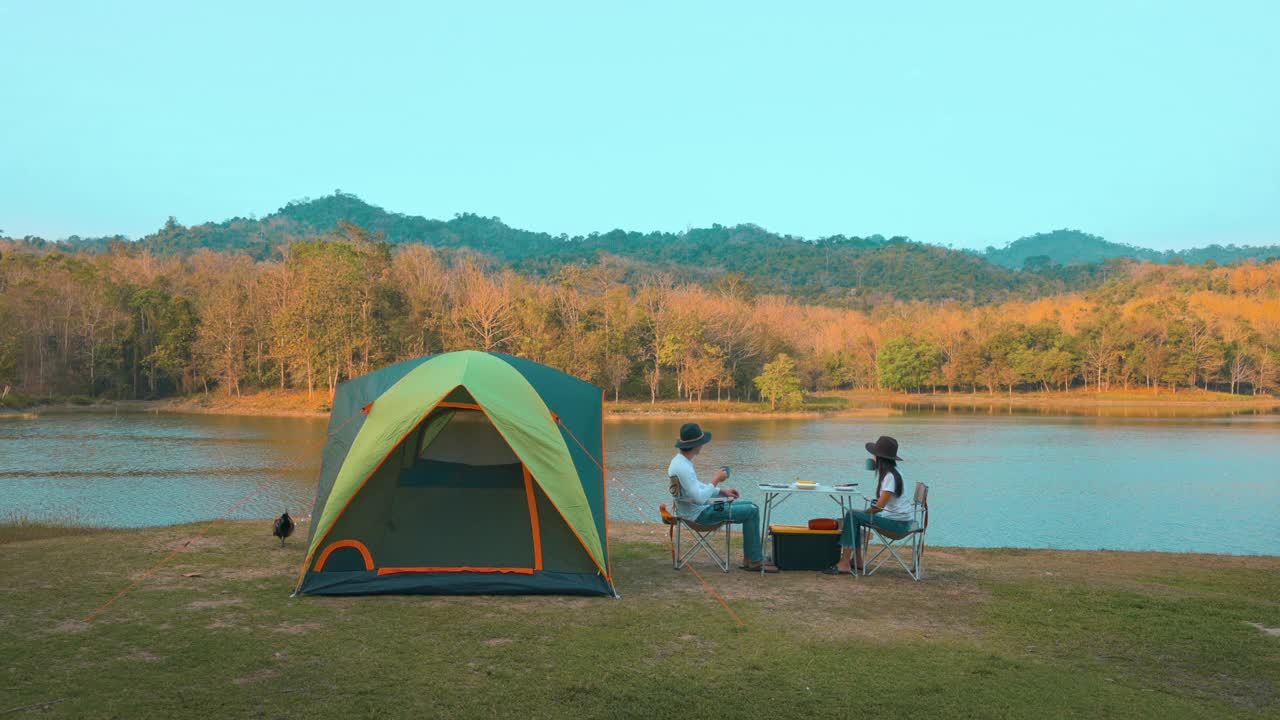 一对旅行情侣在湖边和山景的露营中吃晚餐，旅游目的地，自然旅游概念。视频素材