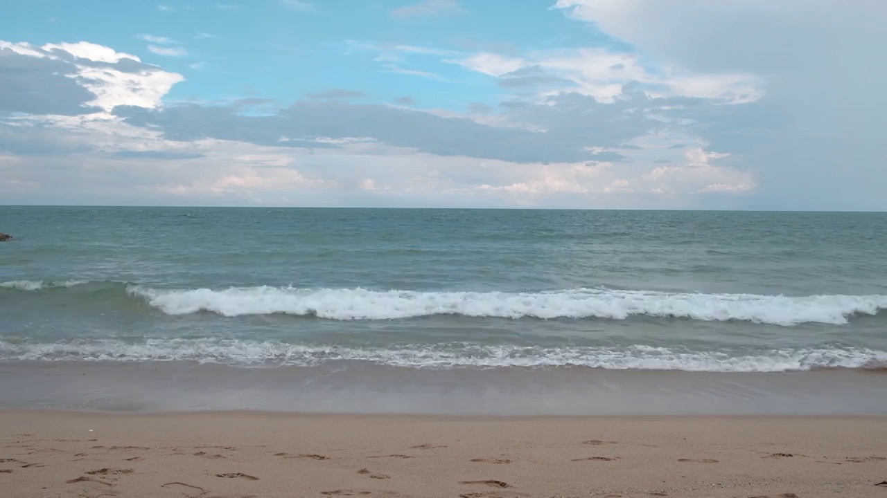 美丽的海边，晴朗的天空。干净的沙滩，海浪一直拍打着海岸。视频素材