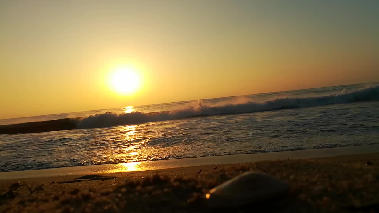 海面上的小波浪日落。金色的夕阳和黄色的阳光。海面上的日出景观。海滩上金色的日出。橙色的日出。视频素材