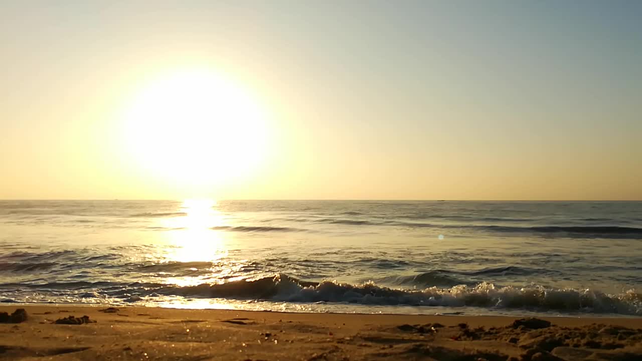 海面上的小波浪日落。金色的夕阳和黄色的阳光。海面上的日出景观。海滩上金色的日出。橙色的日出。视频素材