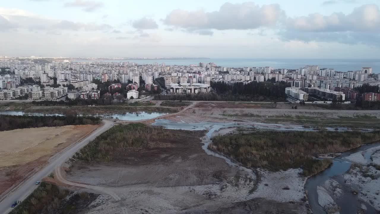 从左到右，无人机可以看到城市内的河床、城市和海景。视频素材