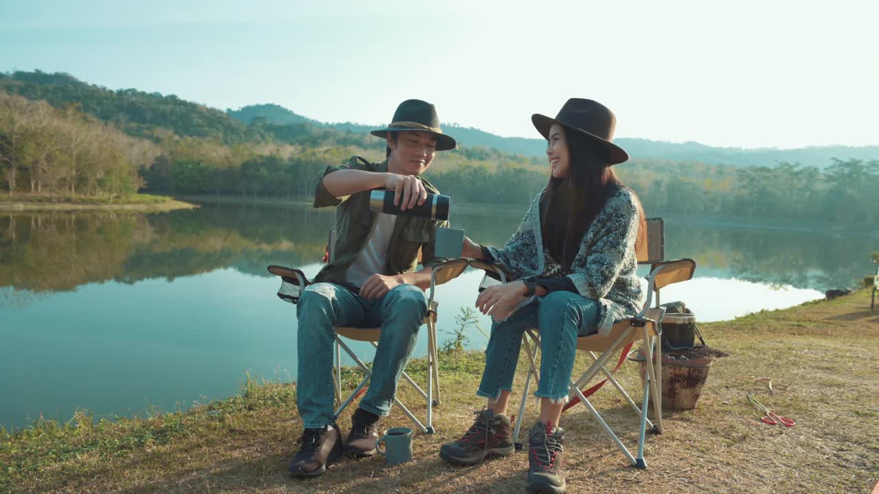 近距离的一个旅行者夫妇正在喝热咖啡的山和河的观点，露营的概念，自然旅游。视频素材