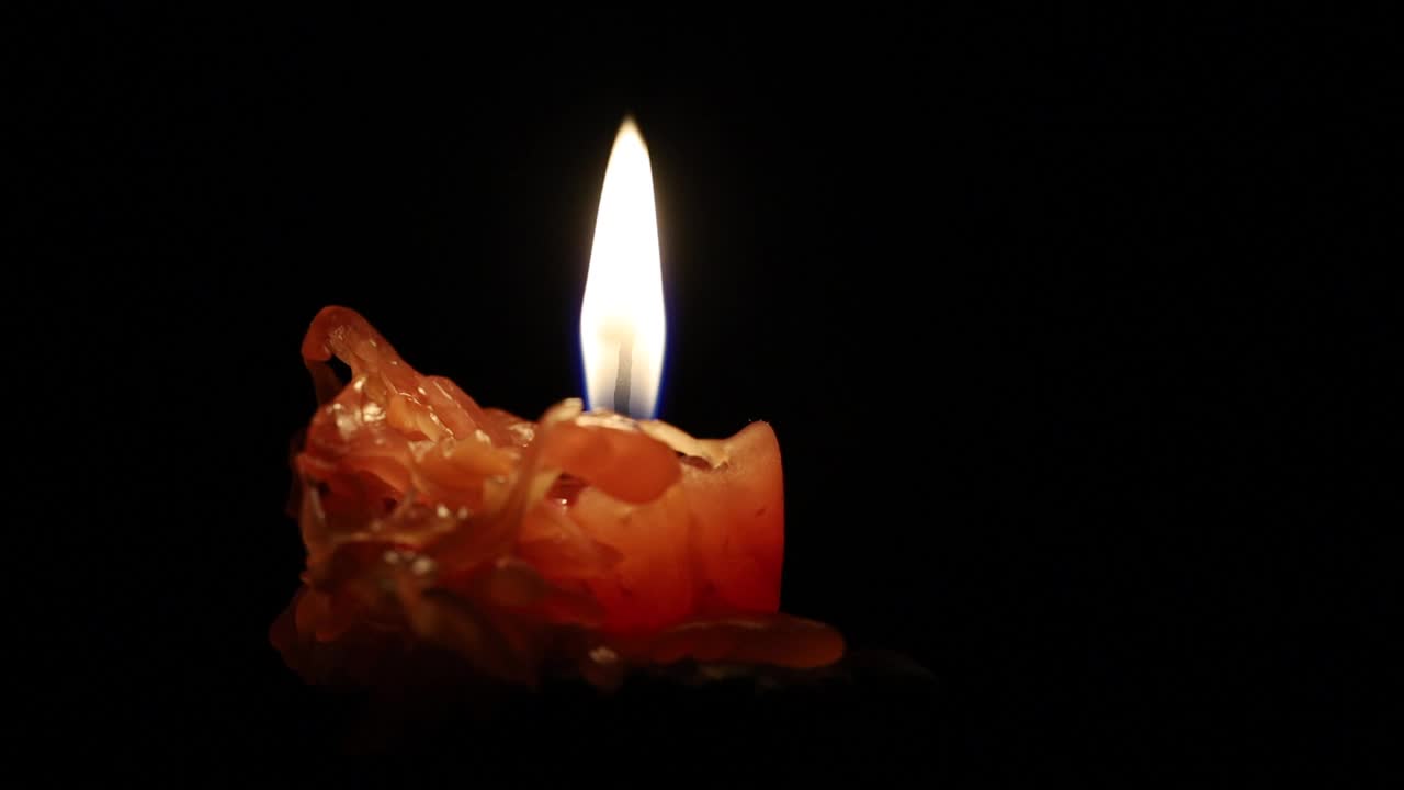 燃烧的黄色蜡烛在一个黑色的背景特写视频素材