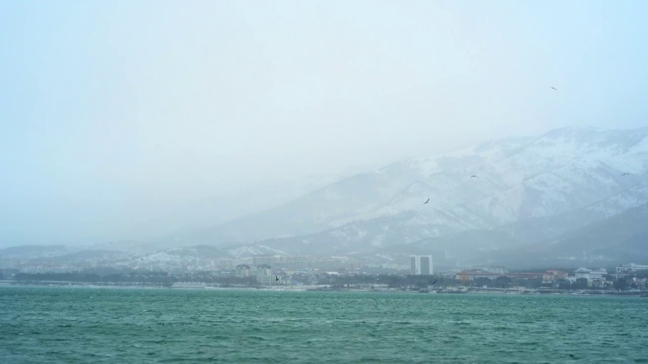 格伦齐克市在冬天的白雪皑皑的天气里，群山被白雪覆盖，海浪和风吹在海湾水面上，没有人在城市中行走视频素材