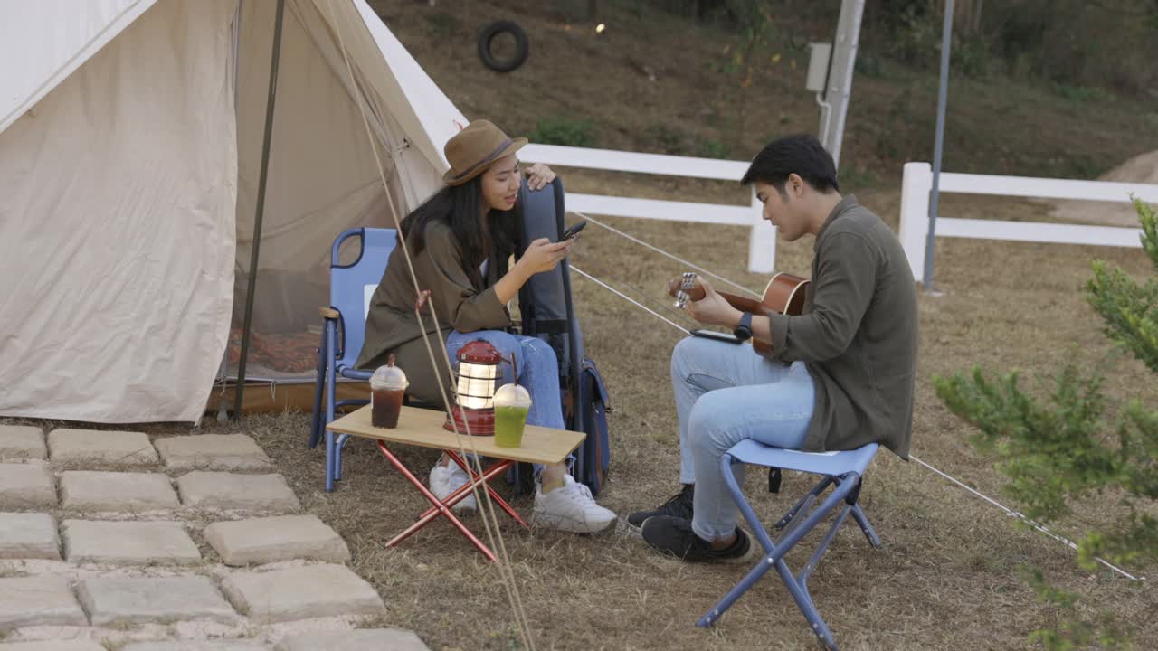 年轻的亚洲夫妇在营地里弹吉他，一起唱歌视频素材