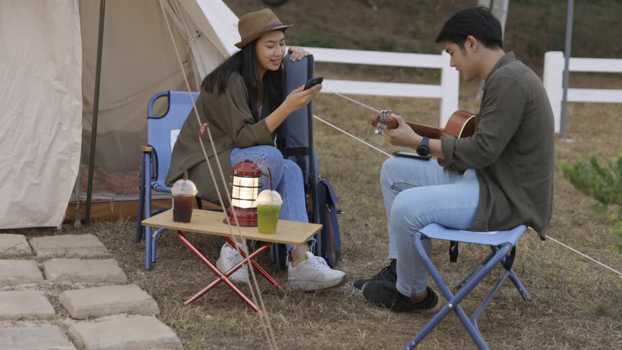 年轻的亚洲夫妇在营地里弹吉他，一起唱歌视频素材