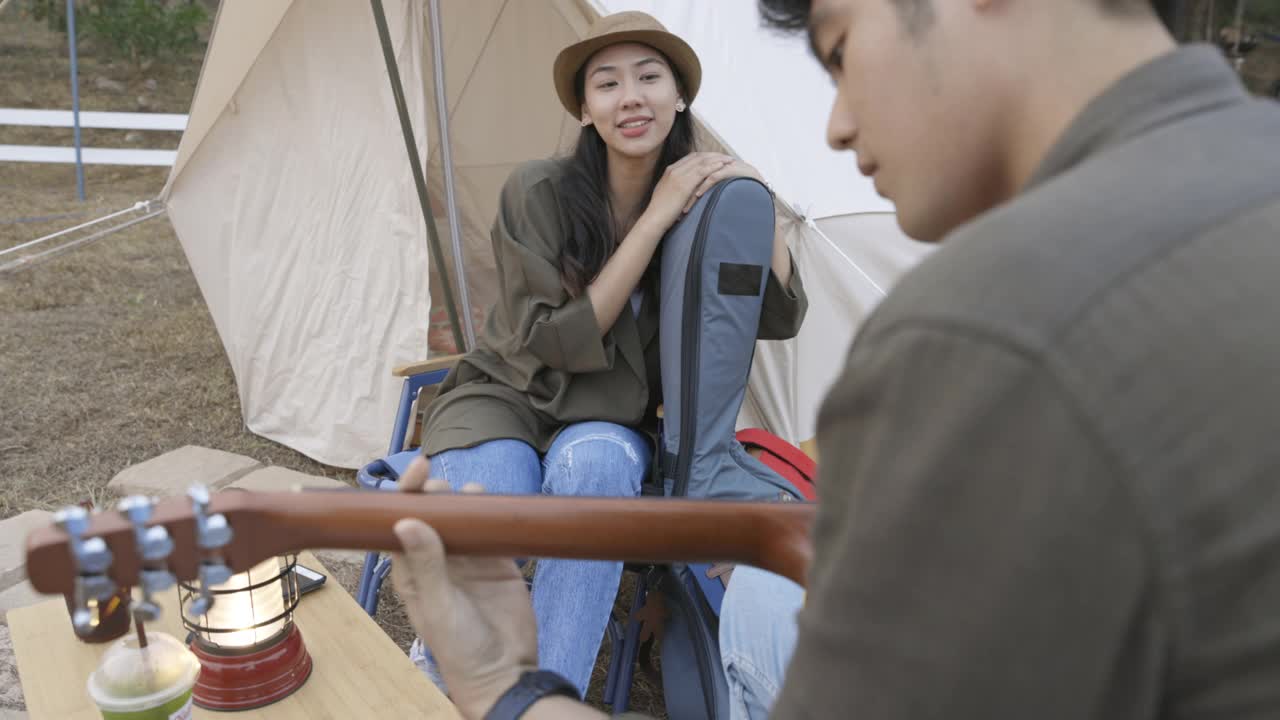 年轻的亚洲夫妇在营地里弹吉他，一起唱歌视频素材