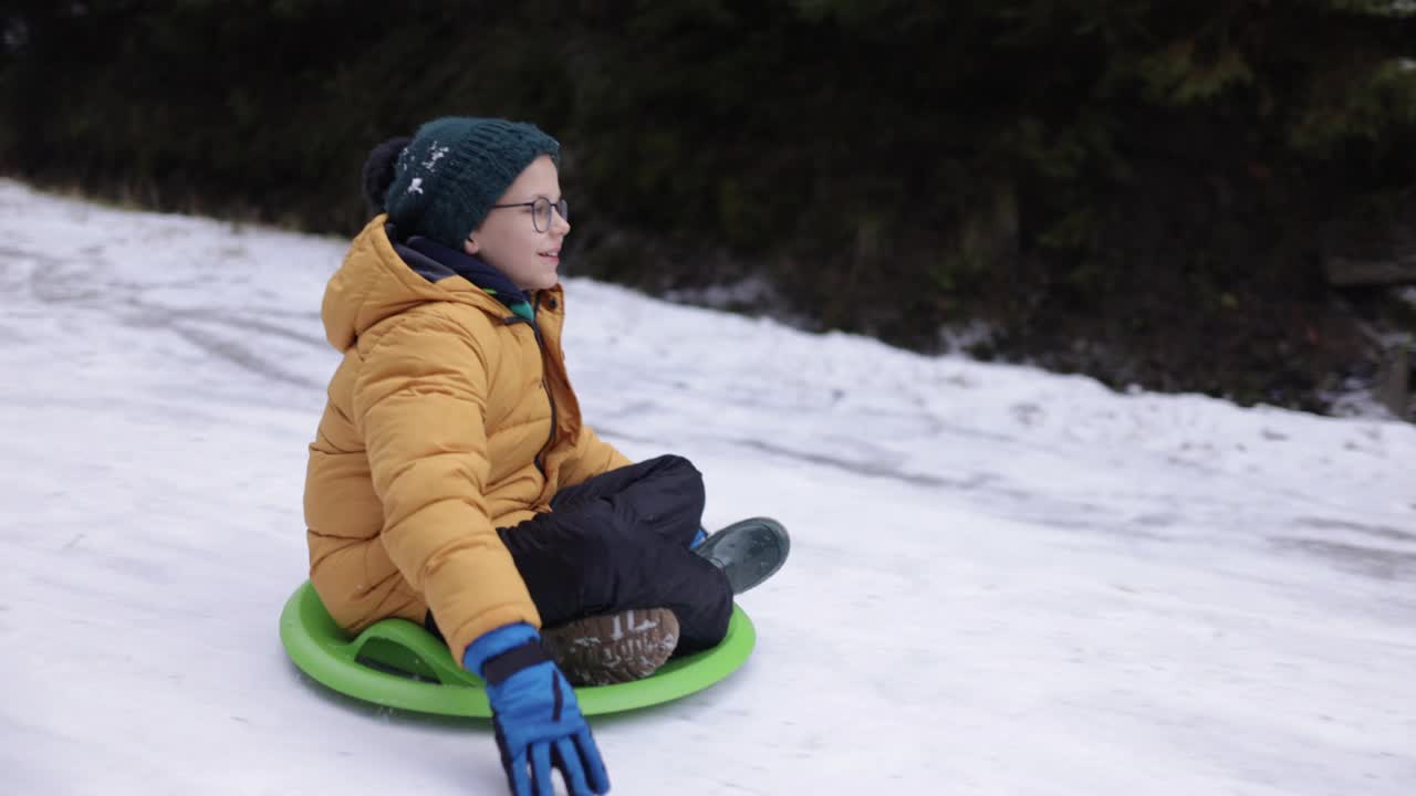 小男孩在冬天的路上滑雪橇视频素材