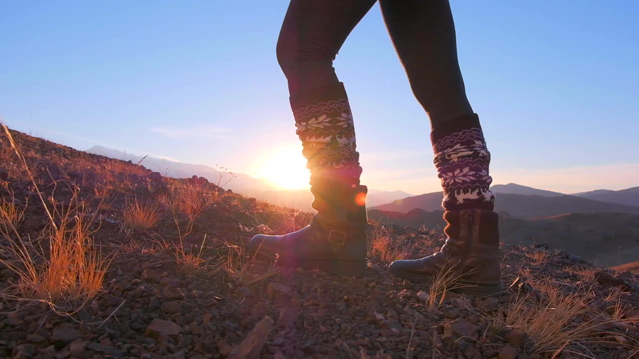 近距离的脚女徒步旅行者女行走和爬上岩石山顶在日落视频素材